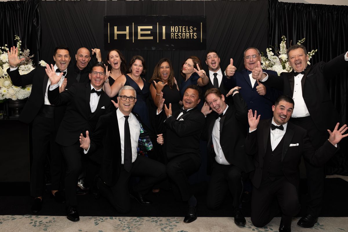 Hotel general managers celebrating together in front of the HEI Hotels backdrop